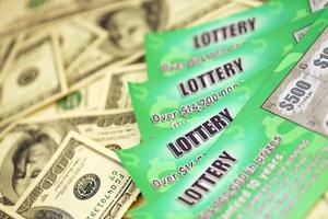 close-up vista de raspadinhas de loteria verde e notas de dólar dos eua. muitos usavam bilhetes de loteria instantâneos falsos com resultados de jogos de azar. vício em jogos de azar foto