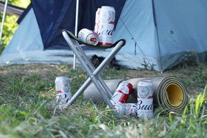 sumy, ucrânia - 01 de agosto de 2021 algumas latas de cerveja de álcool budweiser lager na cadeira de pescador ao ar livre. budweiser é uma marca da anheuser-busch inbev foto