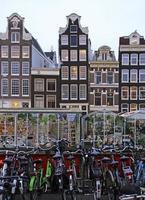 muitas bicicletas e belas casas ao longo de um canal em amsterdã, na Holanda. foto