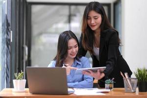 duas jovem empresária asiática discutem com a nova apresentação da ideia do projeto de inicialização, analisam o planejamento e as estatísticas financeiras e o mercado de investimentos no escritório. foto