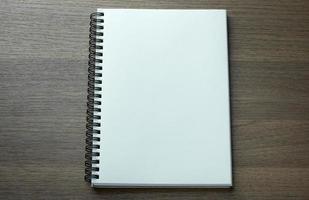 caderno espiral em branco sobre fundo escuro de madeira foto