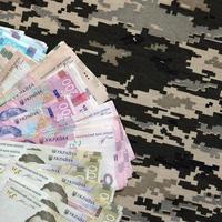 contas de hryvnya ucranianas em tecido com textura de camuflagem pixelizada militar ucraniana. pano com padrão de camuflagem em formas de pixel cinza, marrom e verde foto