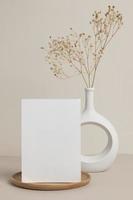 cartão de felicitações vista frontal e flor seca em vaso de cerâmica na mesa
