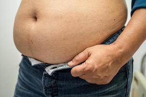 mulher asiática com sobrepeso mostra barriga gorda no escritório. foto