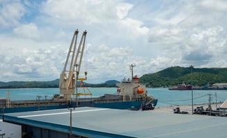 guindaste portuário industrial levanta carregamento de caixa de contêineres de exportação a bordo no porto da tailândia. foto