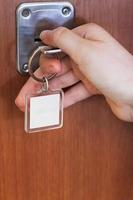 abrindo a porta da casa por chave com chaveiro em branco foto