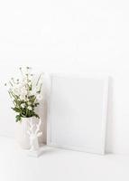 maquete de moldura branca com flores de crisântemo em um vaso em uma mesa branca foto