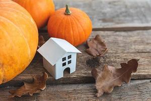 fundo outonal. casa de brinquedo e abóbora em fundo de madeira. espaço de cópia de banner de ação de graças. humor hygge, conceito de mudança de estações. olá outono com festa de halloween em família. foto