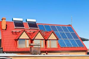 baterias solares e aquecedores no telhado de casa foto