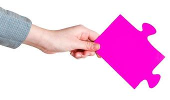 mão feminina segurando grande peça de quebra-cabeça de papel rosa foto