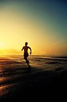 jovem mulher correndo na praia do nascer do sol foto