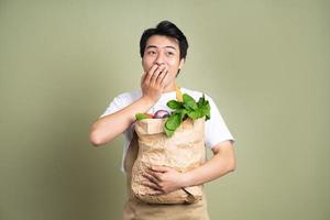 jovem está segurando um saco cheio de legumes, sobre fundo branco. foto