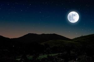 noite estrelada sobre a montanha com lua cheia. foto