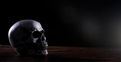 crânio humano de halloween em uma velha mesa de madeira sobre fundo preto. forma de osso do crânio para a cabeça da morte no festival de halloween que mostra horror dente malvado medo e assustador, copie o espaço foto