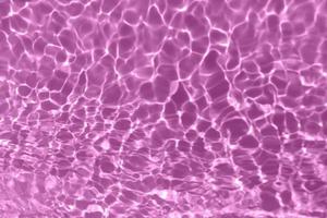 desfocar textura de superfície de água calma transparente de cor roxa transparente turva com respingo, bolha. fundo de ondulação de água roxa brilhante. superfície da água na piscina. cor de água roxa tropical. foto