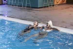 mulheres amigas bebem, coquetel mojito no bar da piscina, usam biquíni hotel de luxo perto da praia na ilha tropical relaxar. mulheres bonitas se divertindo na piscina, bebendo coquetel, sorrindo. foto