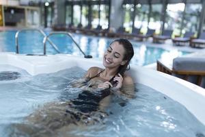 tiro de jovem relaxante em uma jacuzzi. amigos tendo um dia no spa foto