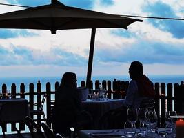 um casal está comendo à mesa de um restaurante com vista para o mar no oeste da Ligúria de finale ligure foto