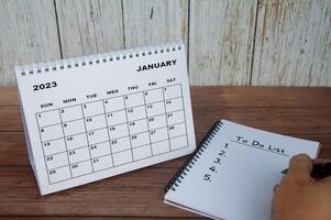 calendário de mesa branco de janeiro de 2023 com notebook com texto - lista de tarefas. calendário e para fazer o conceito de lista foto