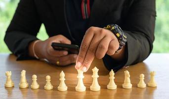 empresário mãos na suíte preta sentado e apontando o rei do xadrez na mesa vintage significado de planejamento e estratégia. conceito de objetivo de decisão e realização.
