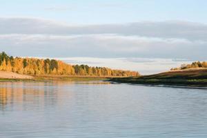 Rio taiga siberiano fluindo, margem de outono do rio cores amarelas da floresta de outono foto