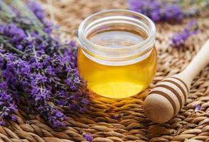 jarra com mel e flores frescas de lavanda foto