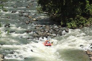 foto de atividades de rafting realizadas por um grupo de pessoas em um rio rochoso com fortes correntes