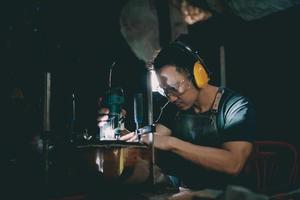 fabricantes de guitarra homem asiático fazendo guitarras acústicas em laboratório. fabricante de guitarra asiático constrói guitarras de alta qualidade para músicos loja de guitarra artesanal. trabalhando bem woodusic, tradição, artesanato antigo. foto