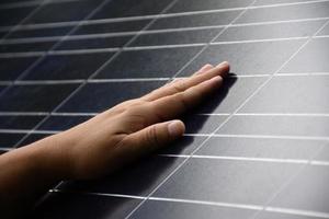 closeup mão no painel de células fotovoltaicas ou solares, foco suave e seletivo na mão, auto painel fotovoltaico verificando por toque na superfície, energia sustentável no conceito de vida humana. foto