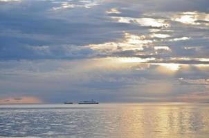 balsa navegando no oceano durante o pôr do sol foto