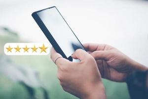 conceito de pesquisa de satisfação do cliente, a mão de um homem usando um smartphone dá uma classificação de 5 estrelas para mostrar o mais alto nível de satisfação com um excelente serviço. foto
