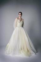 modelo de jovem em um estúdio fotográfico em um vestido de noiva posa levantando dinamicamente as pernas e os braços