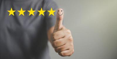 mão com o polegar para cima ícone de rosto sorridente de emoção positiva e 5 estrelas com espaço de cópia. rostos sorridentes emocionais mostrando excelente satisfação. classificação muito impressionado. conceito de serviço e satisfação ao cliente foto