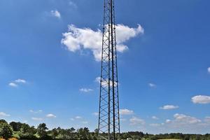 antena elétrica e torre transmissora de comunicação em uma paisagem do norte da Europa contra um céu azul foto