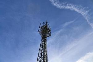 antena elétrica e torre transmissora de comunicação em uma paisagem do norte da Europa contra um céu azul foto