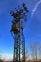 antena elétrica e torre transmissora de comunicação em uma paisagem do norte da Europa contra um céu azul foto