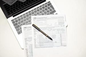 mesa de escritório com formulários fiscais, laptop e caneta, plano de fundo do conceito de negócios foto