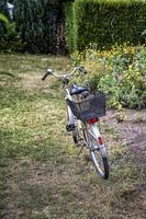 uma bicicleta estacionada em um prado com flores no dia ensolarado de outono. visão vertical foto