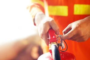 mão de bombeiro segurando o extintor de incêndio. disponível em fundo de danos de conflagração de emergências. conceito de segurança. foto