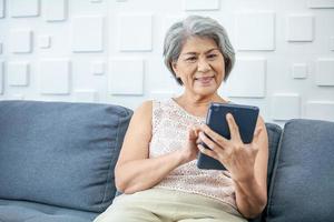 mulher asiática de cabelos grisalhos está segurando o telefone inteligente usando aplicativos online ou compras online. foto