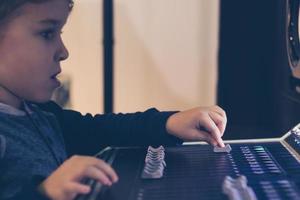 close-up de criança ajustando o volume no mixer de som no estúdio de música. foto