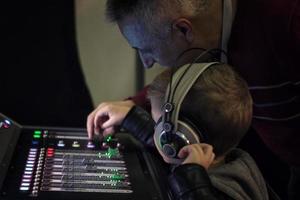 engenheiro de som ensinando menino a ajustar o som no mixer de áudio. foto
