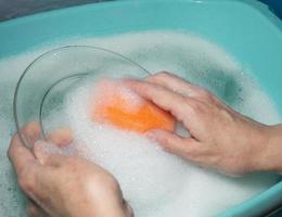 lavar a louça à mão. lavando a placa com uma esponja de espuma. foto