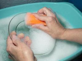 lavar a louça à mão. lavando a placa com uma esponja de espuma. foto