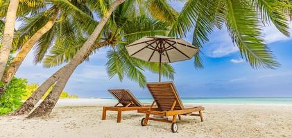 incrível panorama de férias na praia da ilha de verão. duas cadeiras com folhas de palmeira e guarda-chuva, perto do mar, horizonte. paisagem exótica, paraíso tropical, banner de destino de romance de casal. céu de areia do mar foto