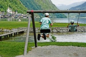 dois irmãos andam em um balanço em hallstatt, áustria. foto