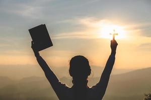 uma mulher está orando a deus na montanha. rezando as mãos com fé na religião e crença em Deus na bênção de fundo. poder de esperança ou amor e devoção. foto