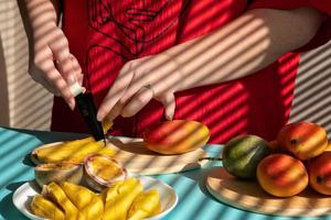 mãos femininas cortam manga e maracujá, café da manhã de frutas foto