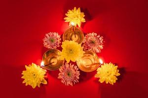 feliz Diwali. celebração hindu tradicional. lâmpadas de óleo diya e flores sobre fundo vermelho. feriado religioso da luz. foto
