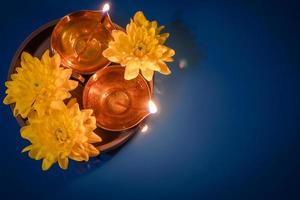 feliz Diwali. lâmpadas de óleo diya e flores amarelas sobre fundo azul. celebrando o tradicional feriado indiano de luz. foto